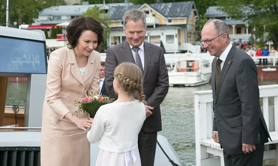 Kerttu Laaksonen, 8,  ojensi kukat rouva Jenni Haukiolle. Presidenttiparia olivat vastassa Naantalin kaupungin edustajat kaupunginvaltuuston puheenjohtaja Mikko Rönnholmin (oik.) johdolla. Copyright © Tasavallan presidentin kanslia 