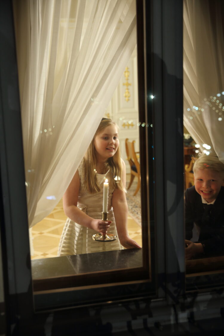 Barnen ställer ljus i fönstret i Gula salen i Presidentens slott. Foto: Juhani Kandell/Republikens presidents kansli