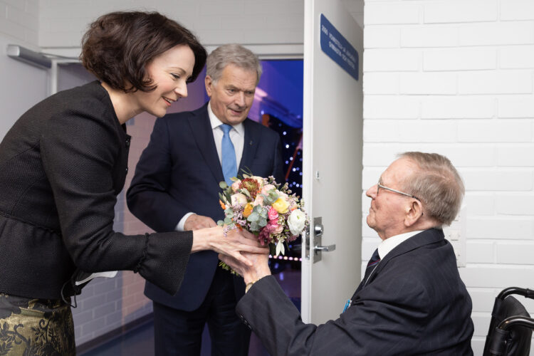 Sotaveteraani Pentti Hooli ojensi kukat tasavallan presidentin puolisolle Jenni Haukiolle. Kuva: Matti Porre/Tasavallan presidentin kanslia