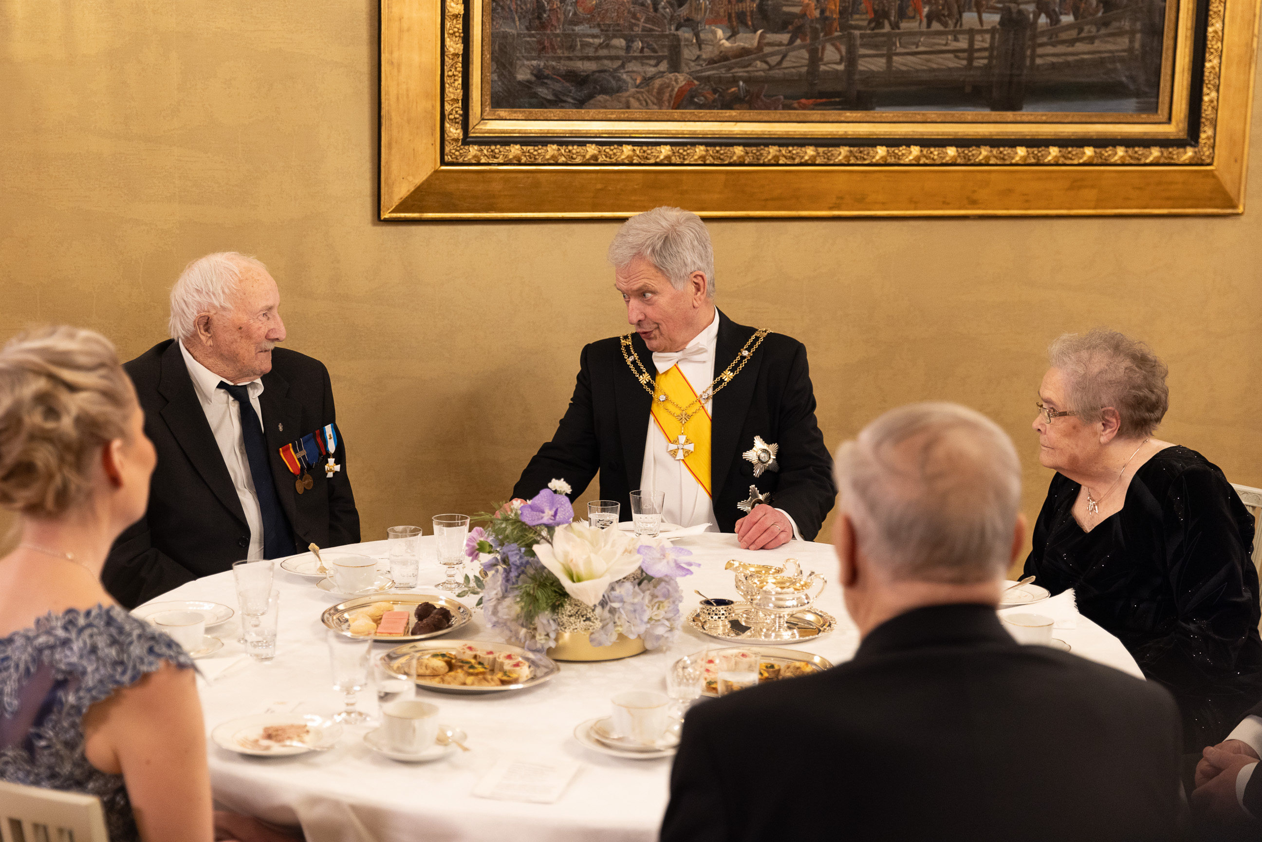 President Niinistö samtalar med krigsveteranerna Aarno Muotka (t.v.), 100 år, och Eila Henttu (t.h.), 95 år. Aarno Muotka deltog i fortsättningskriget på Karelska näset och i Lapplandskriget. Eila Henttu tjänstgjorde som flicklotta och luftvärnslotta. Foto: Matti Porre/Republikens presidents kansli